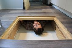 a person laying on the floor with their head in a hole