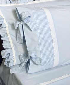 a bed with blue and white ruffles on the pillow cases, along with two pillows