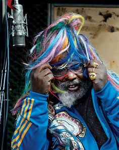 a man with multicolored hair is talking on his cell phone while wearing a blue jacket