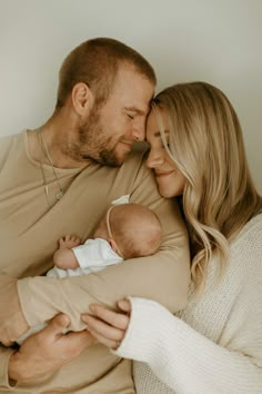 a man and woman holding a baby in their arms