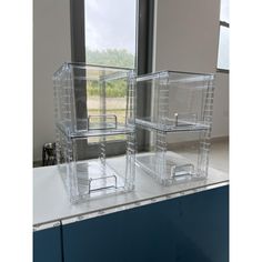 three clear plastic containers sitting on top of a counter next to a large window in a room