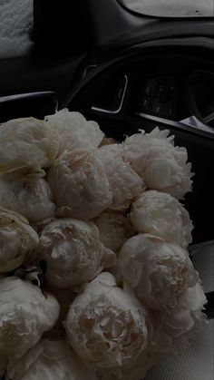 a bunch of white flowers sitting on top of a car dash board next to a steering wheel