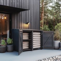 an outdoor storage area with plants and pots on the ground next to a black building