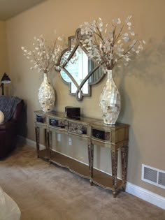 a living room with a couch, mirror and vases on top of the table