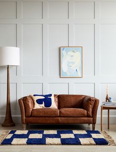 a living room with a brown leather couch and blue rug