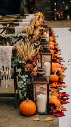 a row of lanterns sitting next to each other filled with pumpkins and greenery