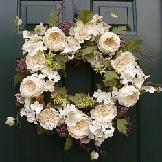 a wreath with white flowers on a green door