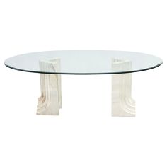 an oval glass table with two white pedestals