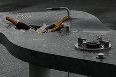 two bottles are in the water on top of a metal table that is partially submerged