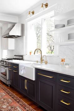 a kitchen with black cabinets and gold pulls on the handles, white marble counter tops