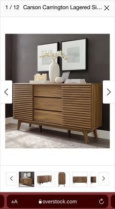 a large wooden dresser sitting on top of a white floor next to a vase and two pictures