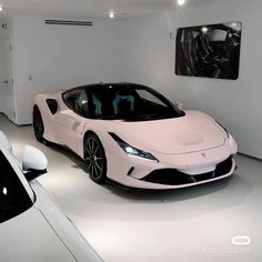 a white sports car is parked in a room with two other cars on the floor