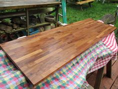 a large wooden cutting board sitting on top of a checkered cloth covered picnic table