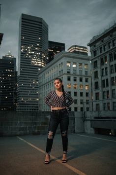 a woman standing in the middle of a city at night with her hands on her hips