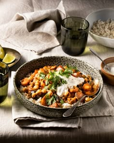 a bowl filled with food sitting on top of a table next to other bowls and utensils