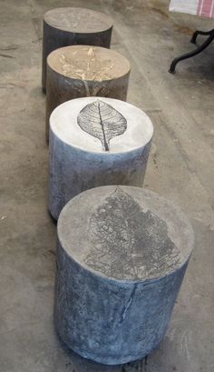 three cement stools sitting next to each other on top of a concrete floor covered in dirt