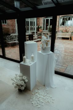 We've added styling to a traditional cake by adding white plinths draping, a cake menu and candles. making it a magical setting. Acrylic Plinth Wedding, Statement Wedding Decor, Wedding Cake Seperator, Engagement Cake Table Decor, Wedding Cake With Bride And Groom, Cake Plinth Display, Plinth Styling, Cake Stand Decor Ideas Display