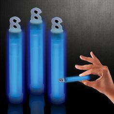 a hand is holding a lighter in front of three blue cylinders