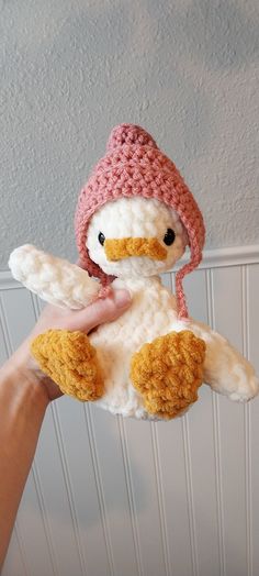 a hand holding a stuffed animal with a knitted hat