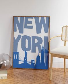 a blue and white new york poster sitting on top of a hard wood floor next to a chair