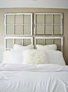 a white bed with pillows on top of it and a headboard made out of old windows