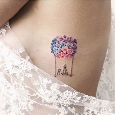 a woman's stomach with a tattoo on it that has flowers in the shape of a balloon