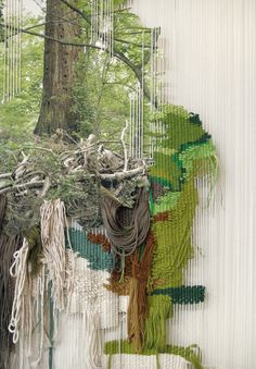 an art work made out of yarn with trees in the background