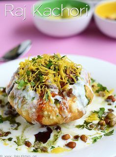 a white plate topped with food on top of a pink tablecloth next to bowls and utensils