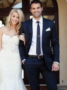 a bride and groom standing in front of a door at their wedding day, posing for the camera