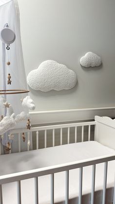 a white crib with two clouds hanging on the wall