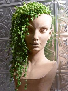 a mannequin with green plants growing out of it's head