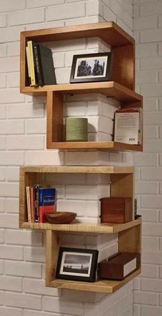 three wooden shelves with books on them against a white brick wall