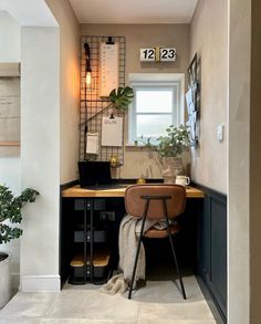 a desk with a laptop on top of it next to a potted plant in front of a window