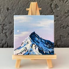 an easel with a painting of a mountain on it