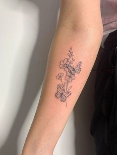 a woman's arm with a tattoo on it that has flowers and butterflies on it