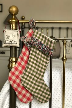 two christmas stockings hanging on a bed rail