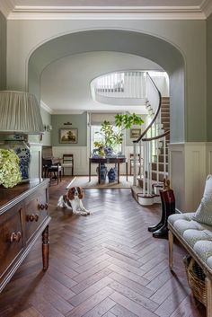 a dog sitting on the floor in a living room next to a table and stairs