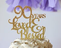 there is a cake that says 90 years loved and beloved on it with gold letters