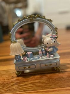 a hello kitty figurine sitting on top of a table next to a mirror