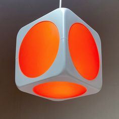 a white and orange light fixture hanging from a ceiling in a room with gray walls