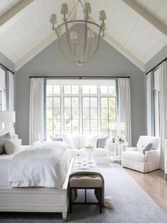 a large bedroom with white furniture and windows in the ceiling, along with a chandelier