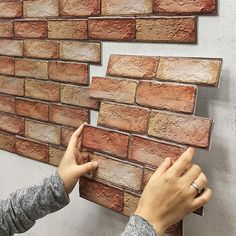 two hands are placing bricks on the wall to make it look like they have been built into