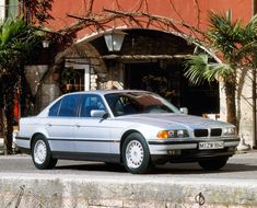 a silver car parked in front of a red building with palm trees on the sidewalk