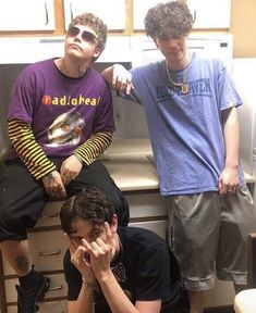 three young men sitting next to each other in front of a stove top oven with their hands on their face