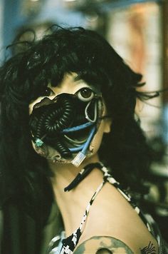 a woman wearing a gas mask with her hair blowing in the wind