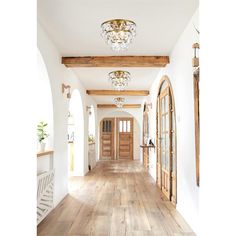 an empty hallway with wooden floors and chandelier hanging from the ceiling above it