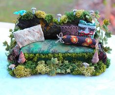 a miniature couch made out of moss and rocks on top of a blue table cloth