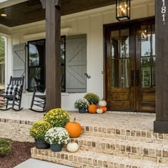 the front porch is decorated with pumpkins and flowers