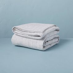 two folded linen sheets on top of each other in front of a light blue background