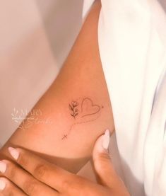 a woman's arm with a small flower tattoo on the left side of her body